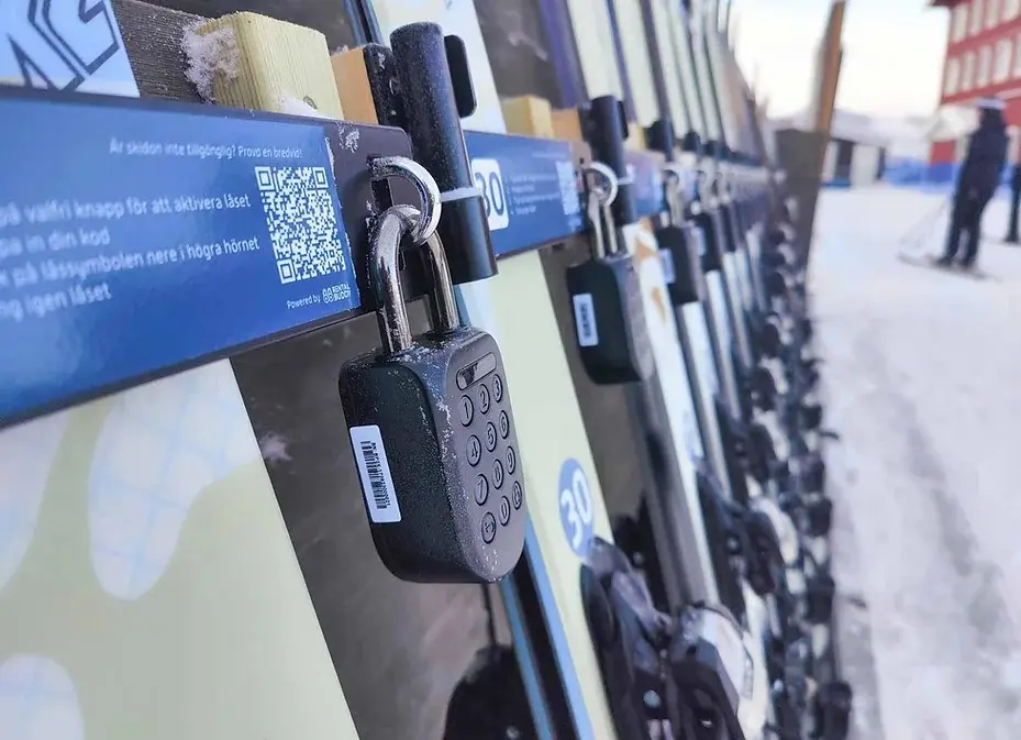 An igloo padlock securing skis at an unmanned ski rental kiosk